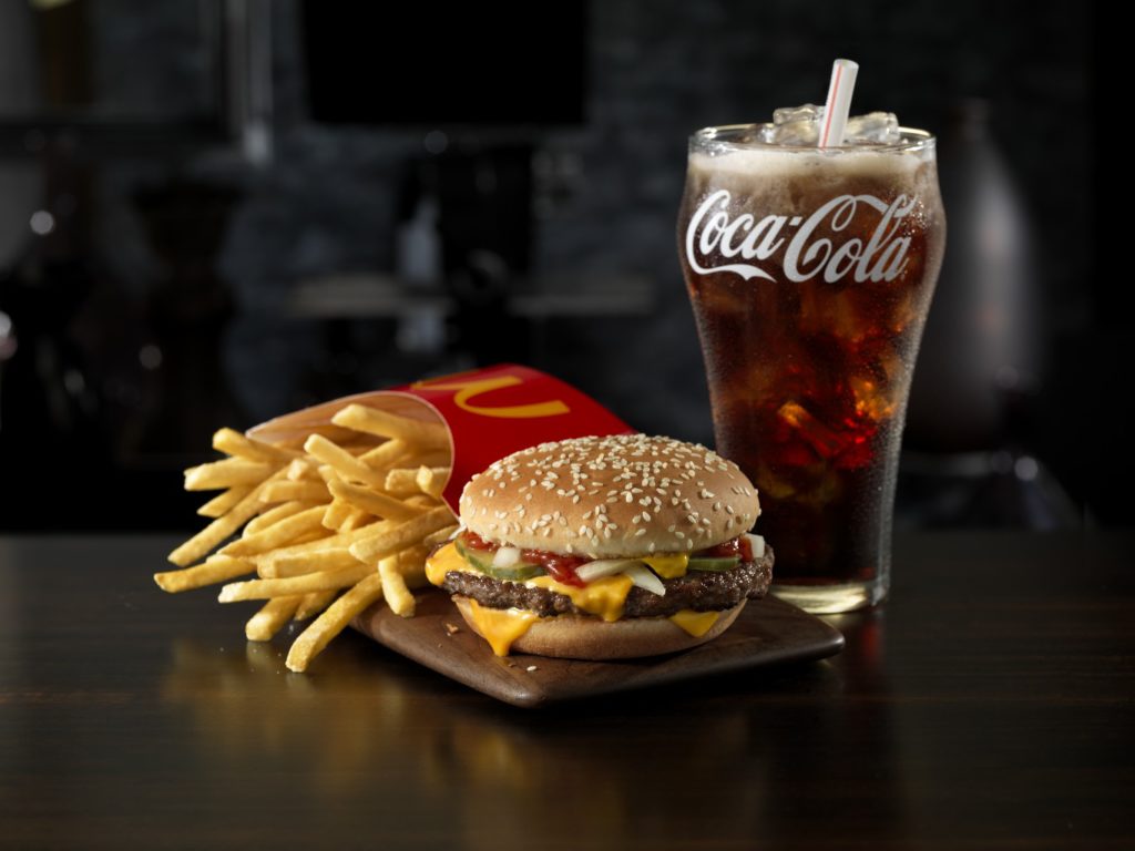 Quarter Pounder with Cheese Extra Value Meal (QPC): Sandwich, Fries and Coca-Cola in bell glass, dark, wood table surface, dark, indoor background