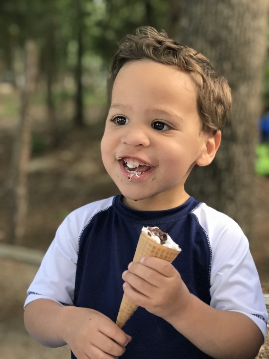 Boy smiling after taking a bite of marshmallow and chocolate in a s'mores cone