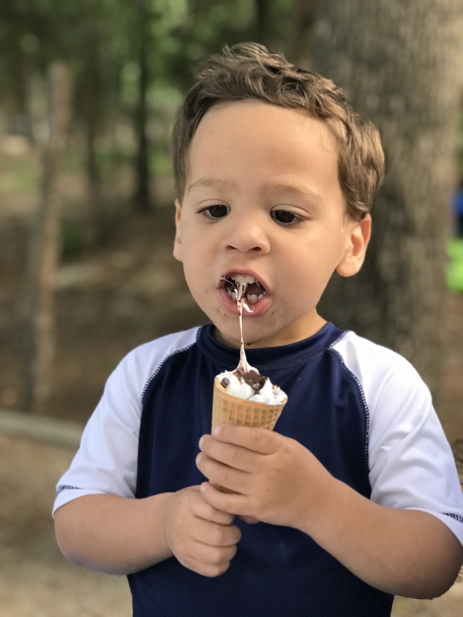 George eating gooey marshmallow from a campfire s'mores cone