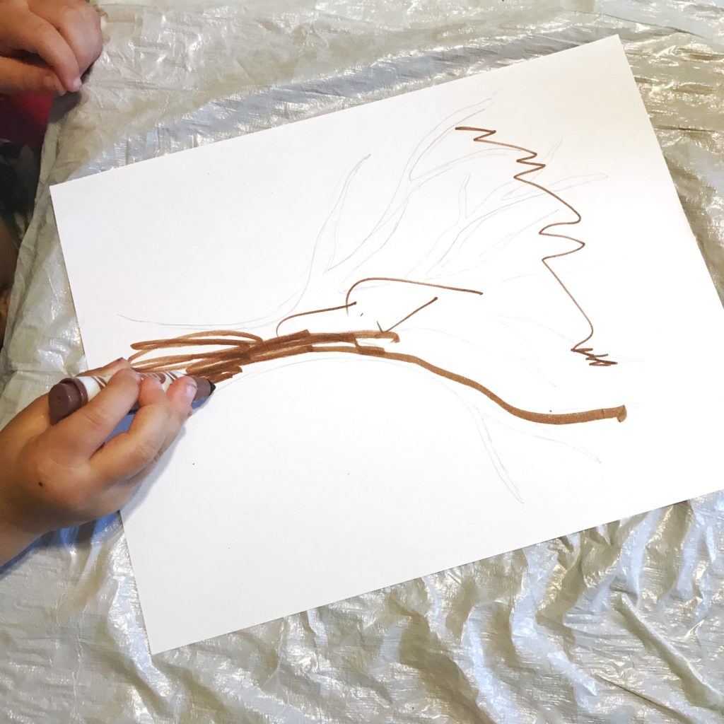 Toddler traces a tree for his fall tree painting.