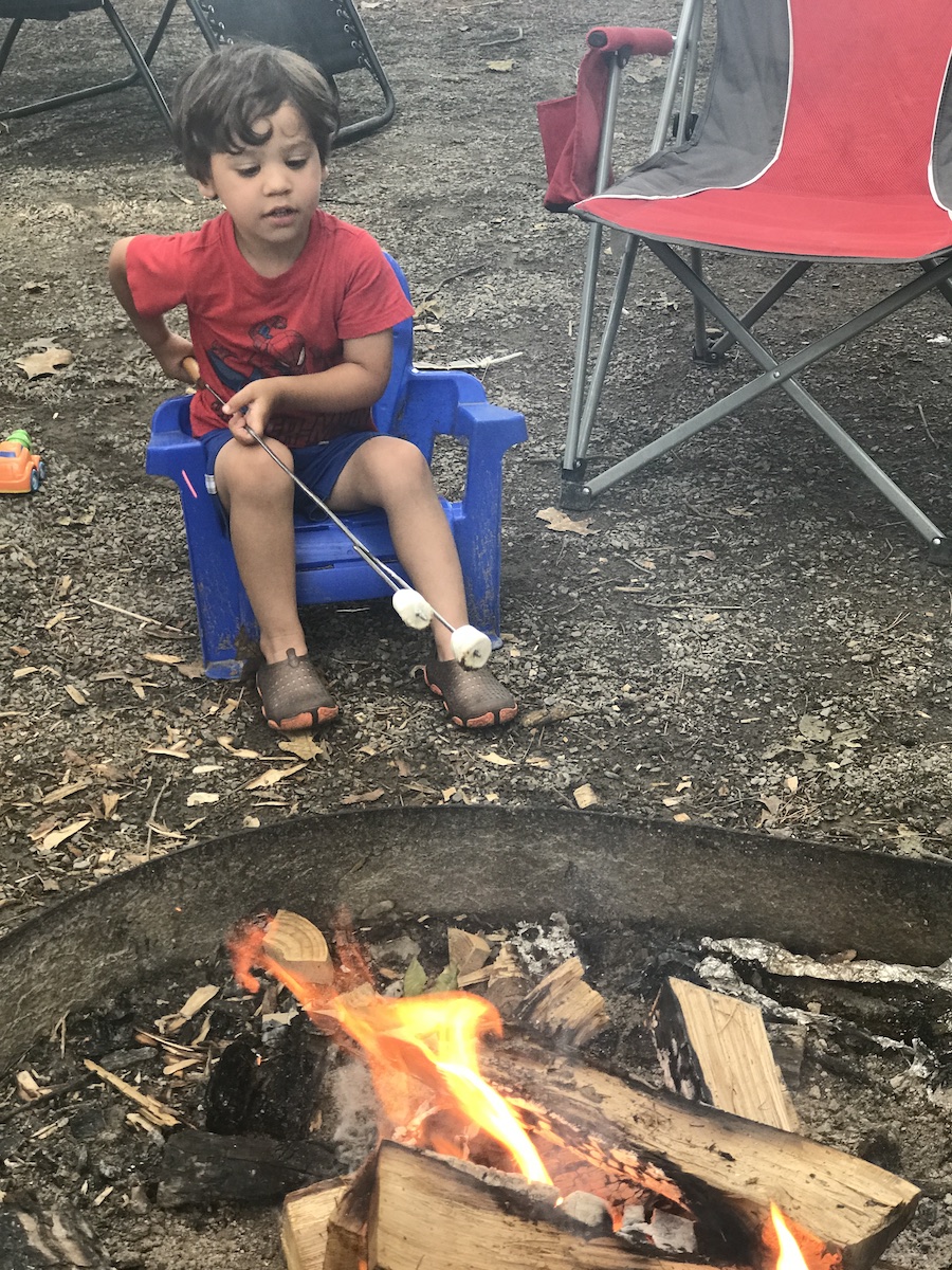 George practices campfire safety as he roasts a marshmallow over the fire.